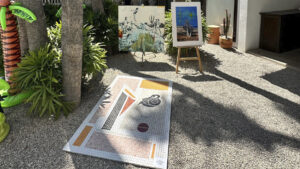 Instalación artística al aire libre con una obra colocada sobre el suelo y pinturas exhibidas en un jardín durante una edición de ABC ART BAJA CALIFORNIA.