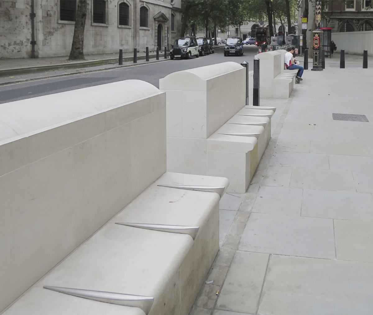Banca urbana con divisores metálicos diseñada para impedir que las personas se recuesten, ejemplo de arquitectura hostil en espacio público