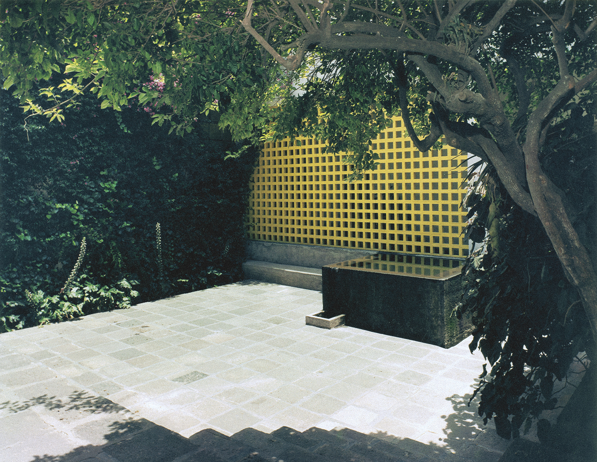 Jardín interior de la Capilla de las Capuchinas de Luis Barragán en CDMX con celosía amarilla y pileta de agua.
