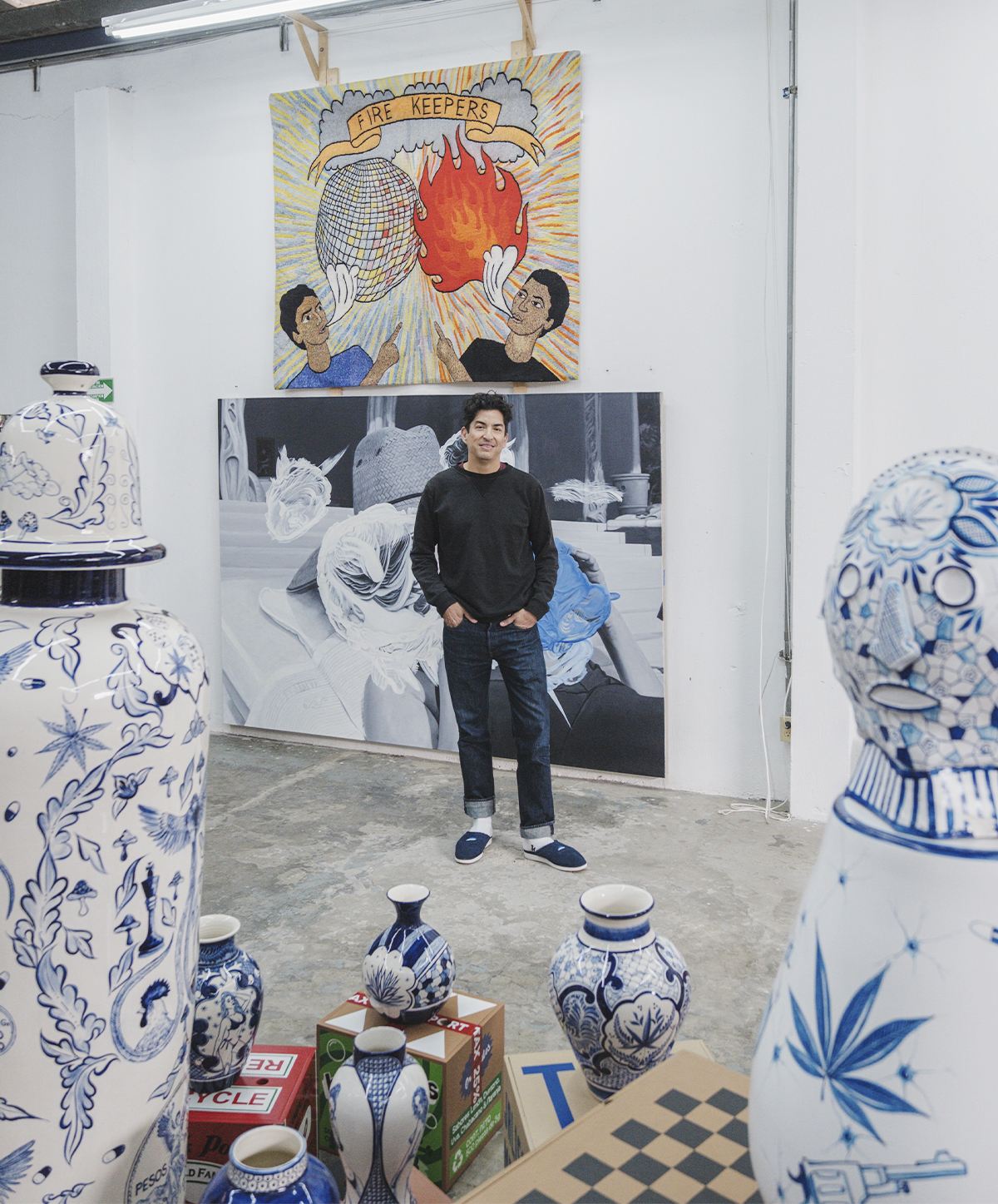 Eduardo Sarabia posa en su estudio de Guadalajara rodeado de grandes jarrones de cerámica azul y blanca intervenidos con ilustraciones contemporáneas y referencias culturales mexicanas.