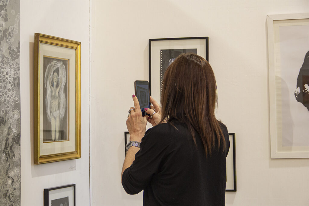 Visitante observa y fotografía obras en +Feria Arte Contemporáneo de Santa Fe