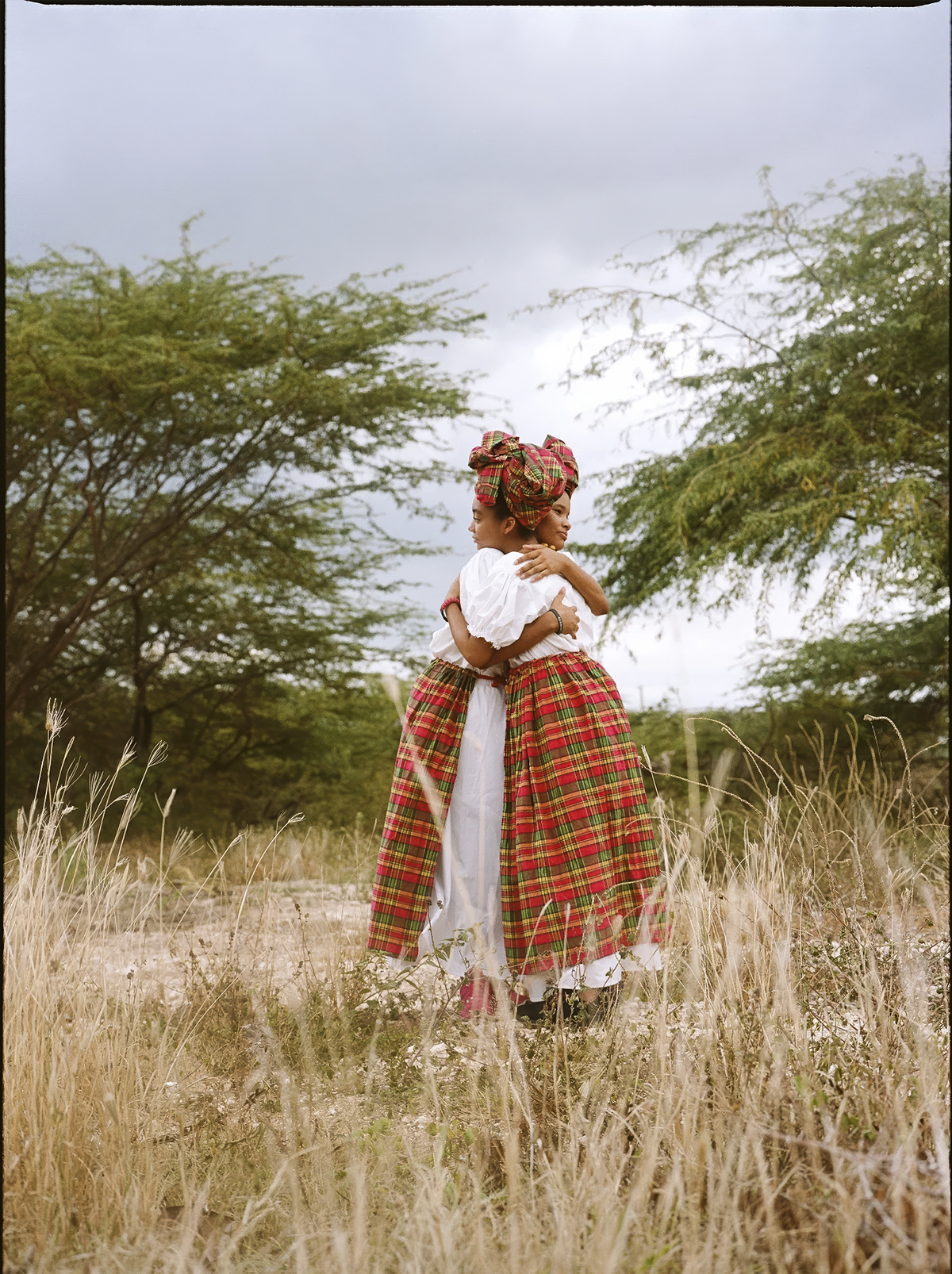 Dos mujeres rurales abrazándose en un paisaje natural fotografiadas por Cecilia Duarte en América Latina.