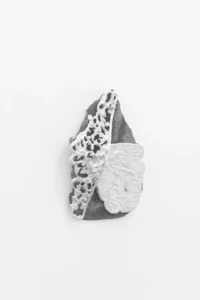 Relieve blanco de formas orgánicas sobre base gris, montado en un muro blanco