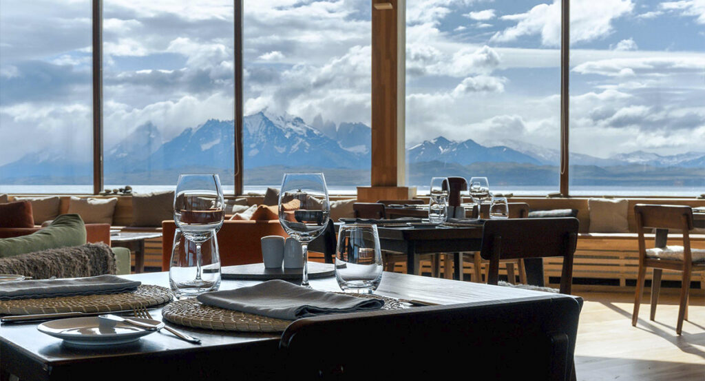 Mesas preparadas junto a grandes ventanales con vistas a las montañas de Torres del Paine.