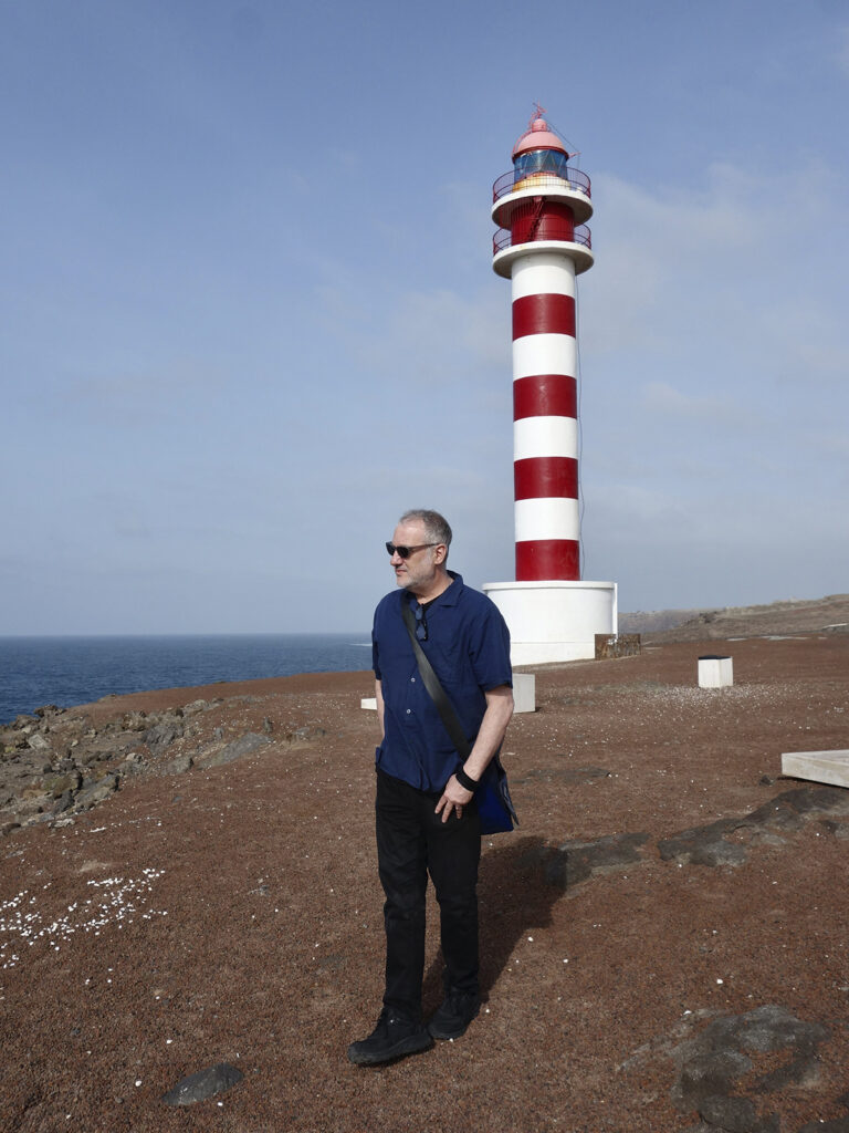 El fotógrafo estadounidense Spencer Tunick posa junto al Faro de Gáldar, en Gran Canaria, donde realizará Gran Spectrum en julio de 2026.
