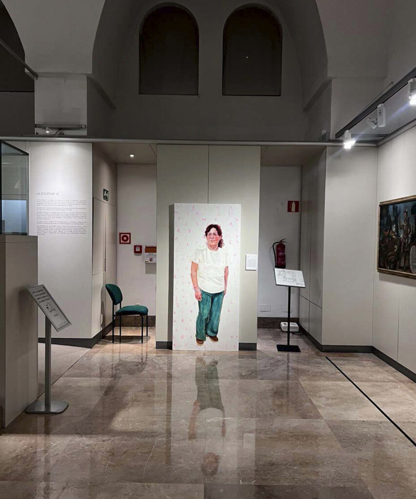 Vista de una sala del Museo de América de Madrid con el retrato de una trabajadora doméstica latinoamericana expuesto en el centro, como parte de la exposición Cama Adentro.