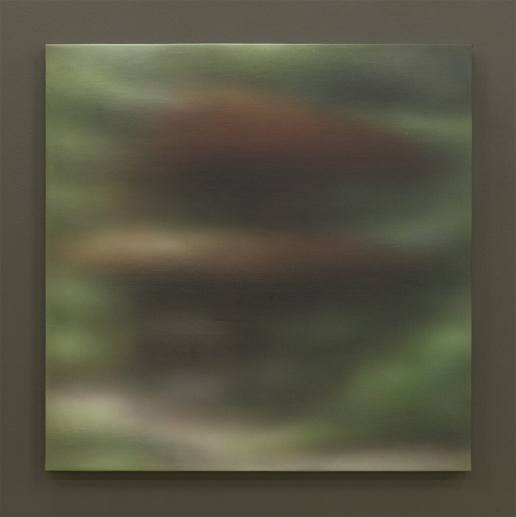 Pintura abstracta de tonos verdes y marrones con efecto desenfocado que sugiere una estructura arquitectónica rodeada de vegetación, presentada sobre un muro neutro.