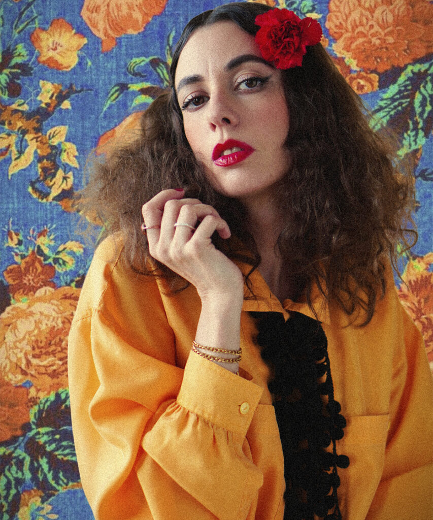 Sofía Comas sostiene una rosa roja sobre un fondo amarillo en una imagen promocional de Tecuán Caroca.