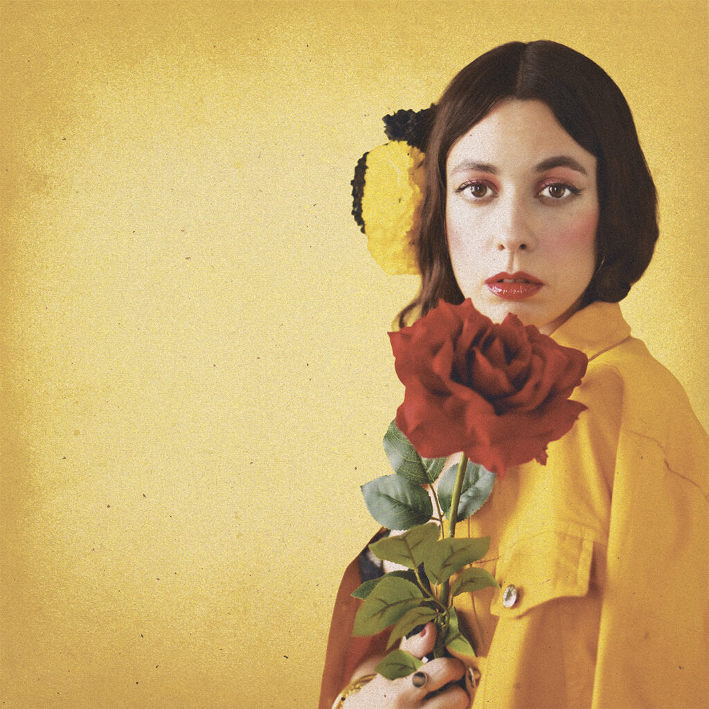 Retrato de Sofía Comas con una flor roja en el cabello y fondo floral colorido.