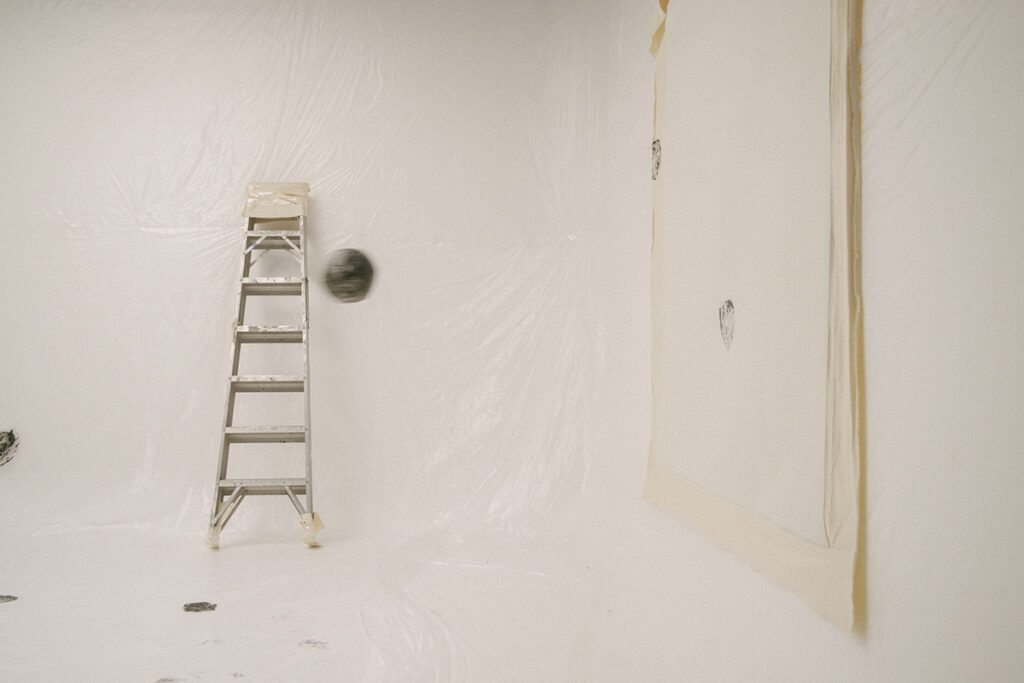Una imagen de arte conceptual. Un espacio de esquina de galería minimalista con paredes y suelo blancos, que parecen estar cubiertos con una capa de plástico transparente.