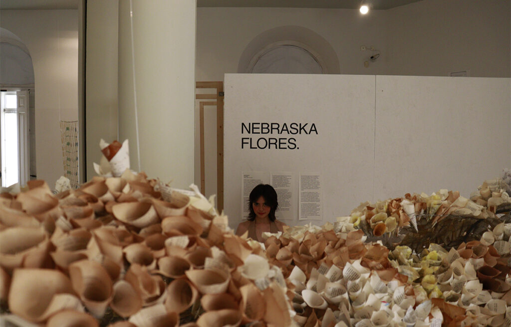 Nebraska Flores Espín detrás de una instalación formada por piezas de papel y cerámica durante una exposición de arte contemporáneo.