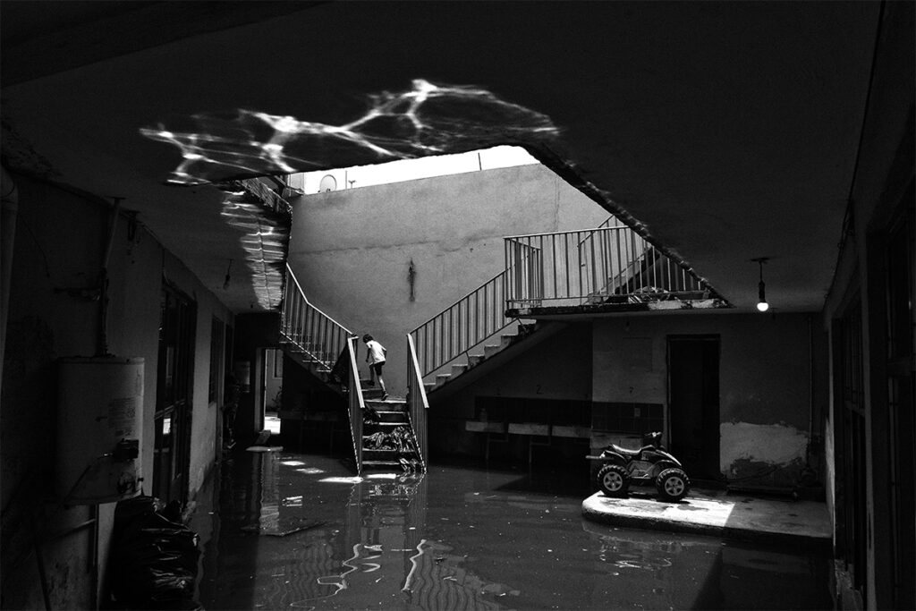 Niño sube unas escaleras mientras un conjunto habitacional permanece inundado en Chalco, Estado de México.