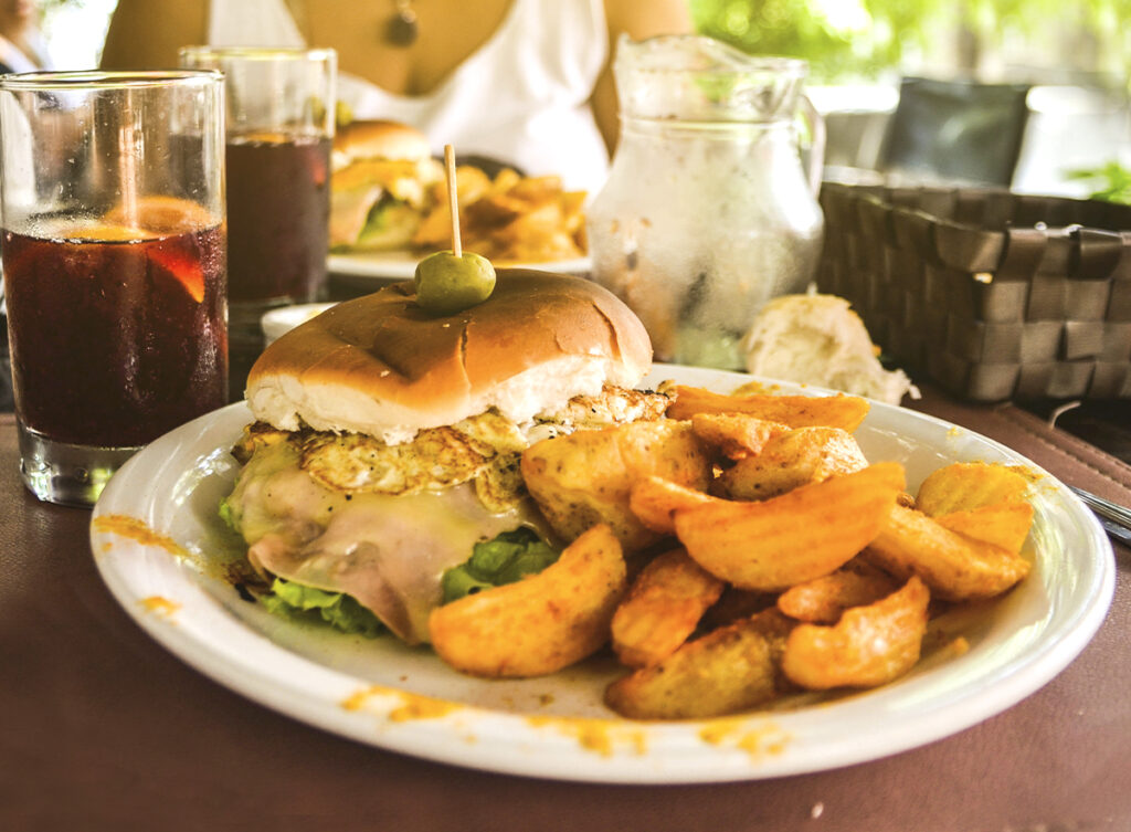 Chivito canadiense servido con papas rústicas en un restaurante de Montevideo.