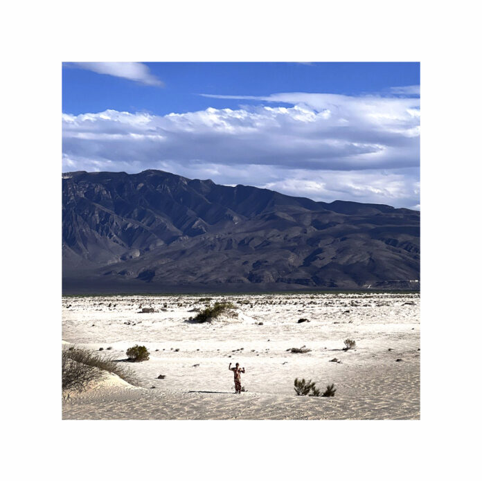 Paisaje desértico con montañas al fondo y una figura humana en la distancia, fotografiado por Gabriel Sánchez Viveros.