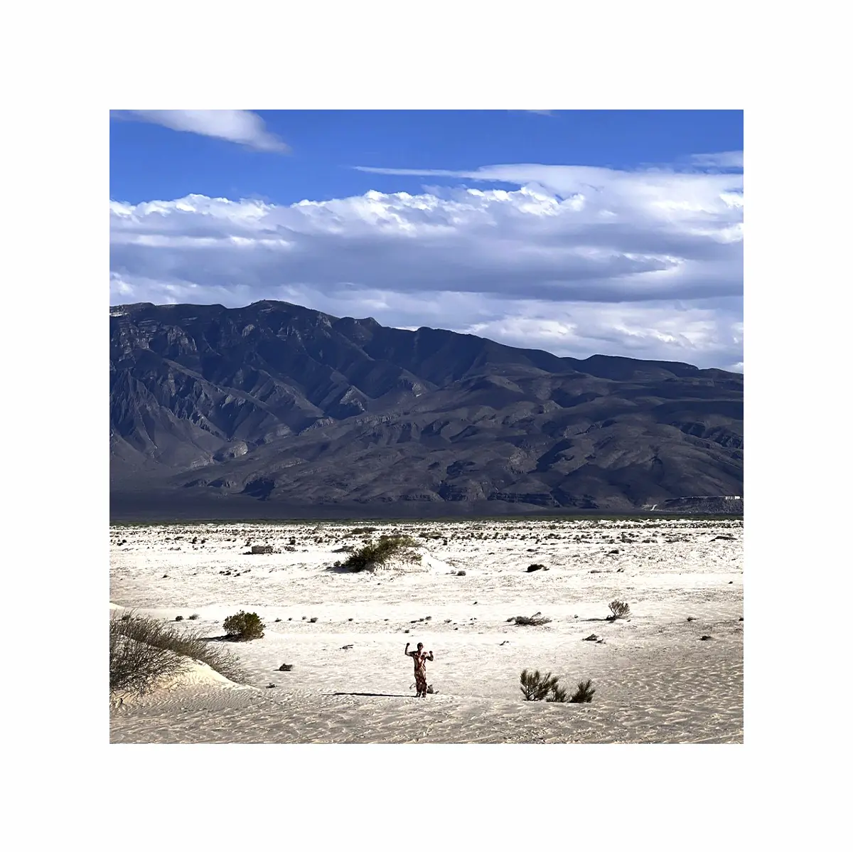 Paisaje desértico con montañas al fondo y una figura humana en la distancia, fotografiado por Gabriel Sánchez Viveros.