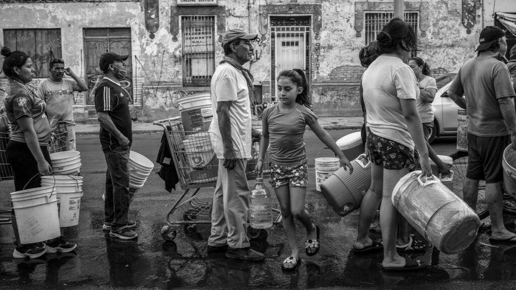 Personas cargan cubetas y garrafones durante una jornada de distribución de agua en México.