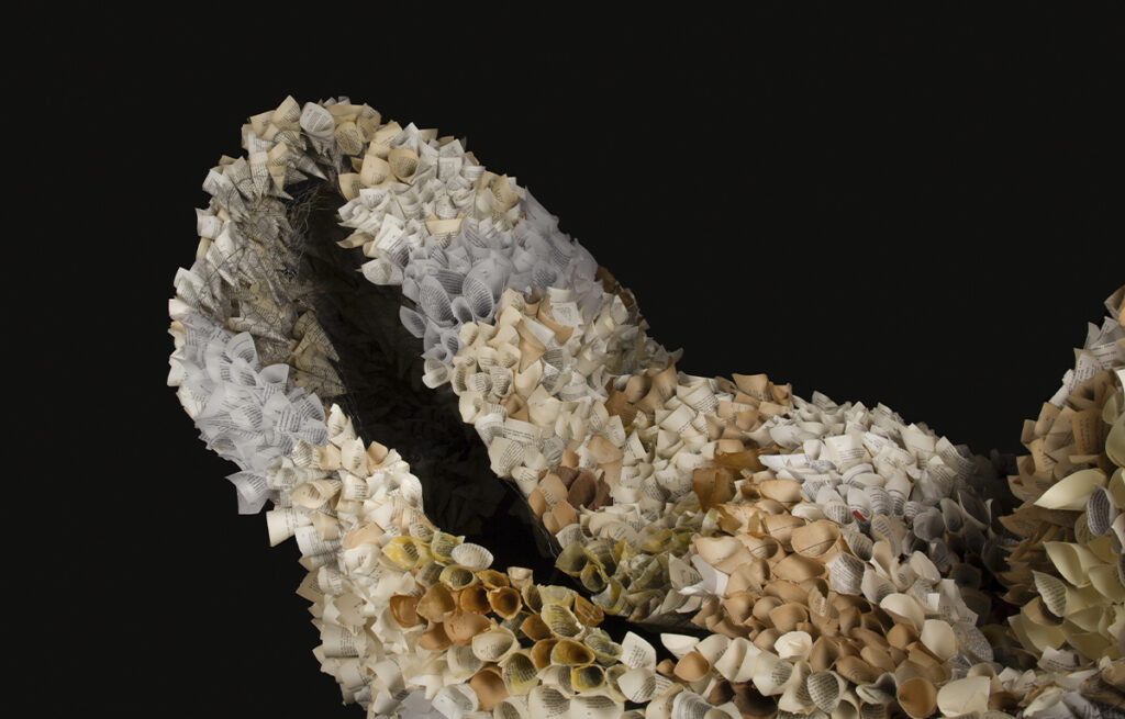 Detalle de una escultura contemporánea realizada con papel enrollado y materiales reutilizados que recrean formas inspiradas en ecosistemas naturales.