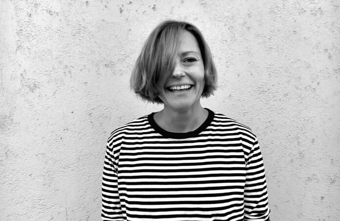 Retrato en blanco y negro de la curadora Polina Stroganova sonriendo frente a un muro.