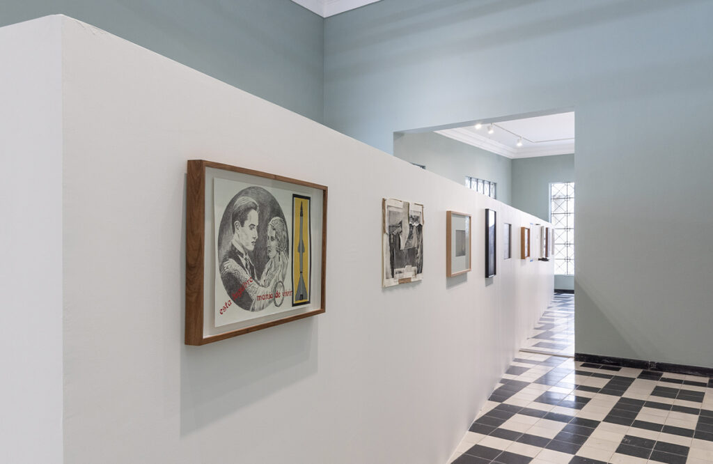 Vista lateral de una exposición de arte contemporáneo con obras enmarcadas distribuidas a lo largo del recorrido.