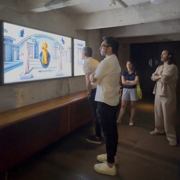 Miembros del equipo de JUSTQRO observan una obra de arte digital proyectada en una pantalla de gran formato durante una visita a un espacio cultural en Querétaro.