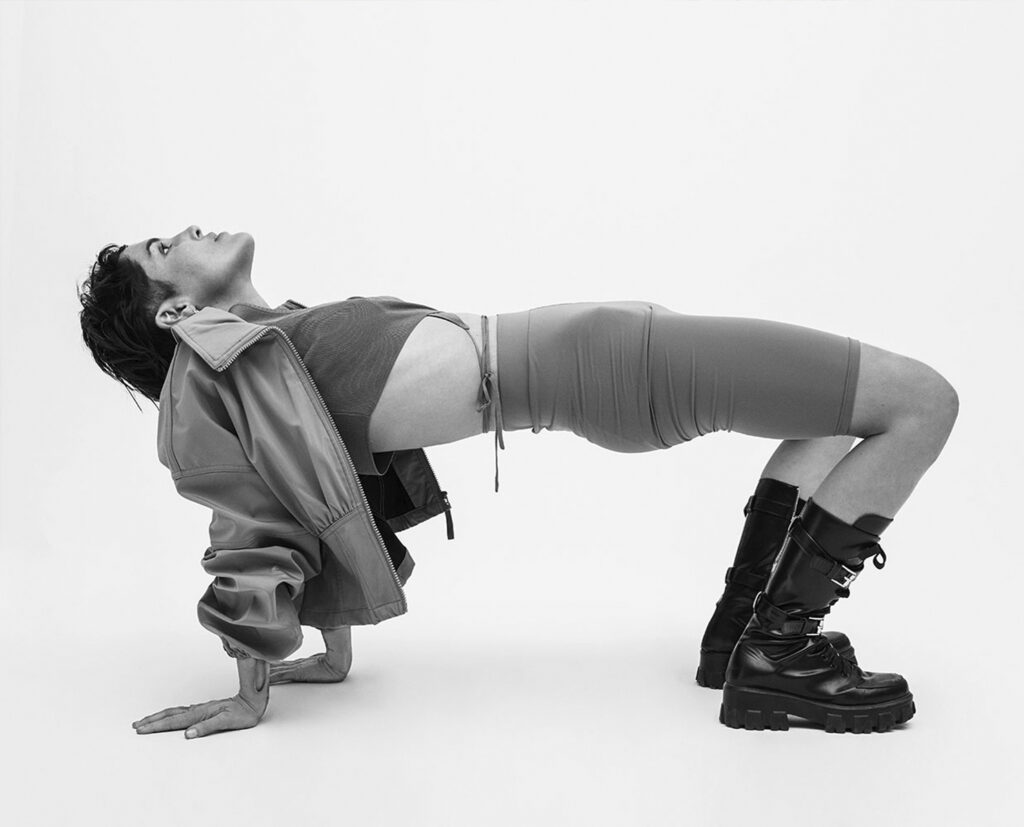 Una toma dinámica en blanco y negro de Straube inclinada hacia adelante, con los brazos extendidos, capturando la energía del pop experimental de Rubio.