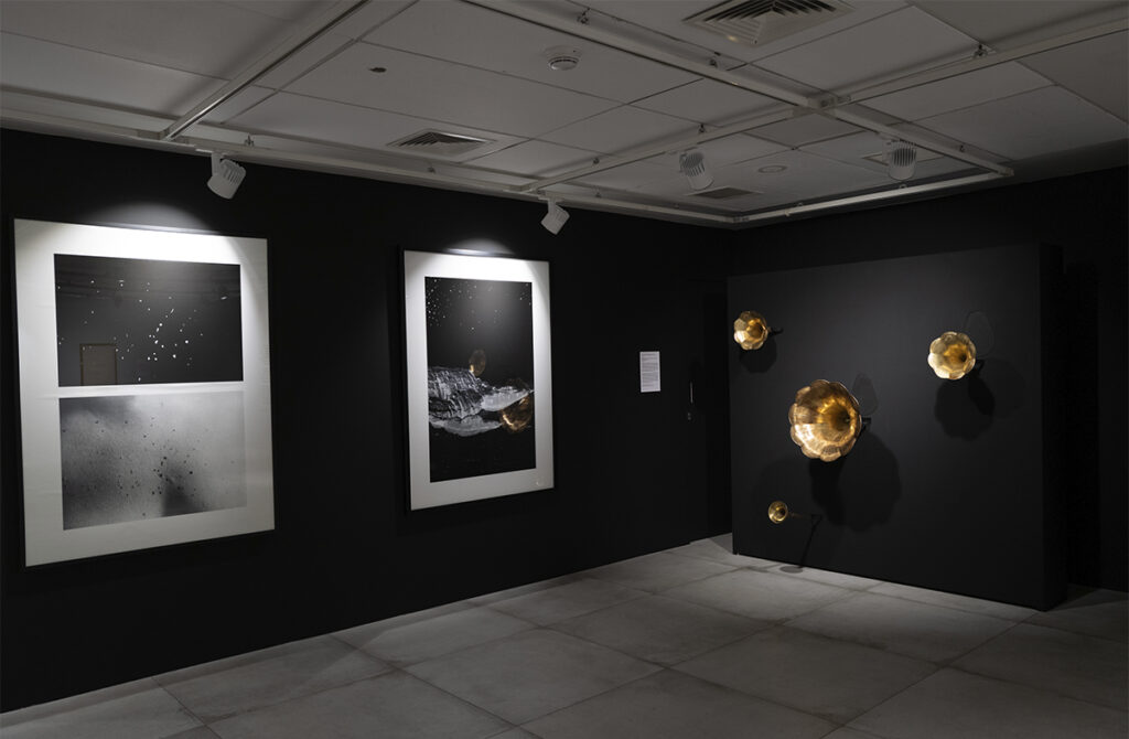 Vista de una instalación de Mariajosé Fernández-Plenge con fotografías, esculturas sonoras y piezas murales en una sala de exposición.