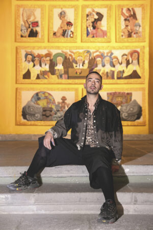Pepx Romero sentado frente a Performance es el nuevo muralismo, retablo monumental instalado en el Museo Ex Teresa Arte Actual.