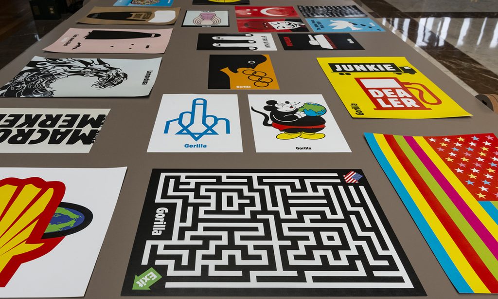 Carteles de colores con ilustraciones y tipografía dispuestos sobre una mesa.