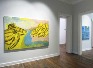 Pintura de Emi Winter con grandes racimos de plátanos amarillos, presentada en la exposición Trópico de Jersey en Galería Ethra.