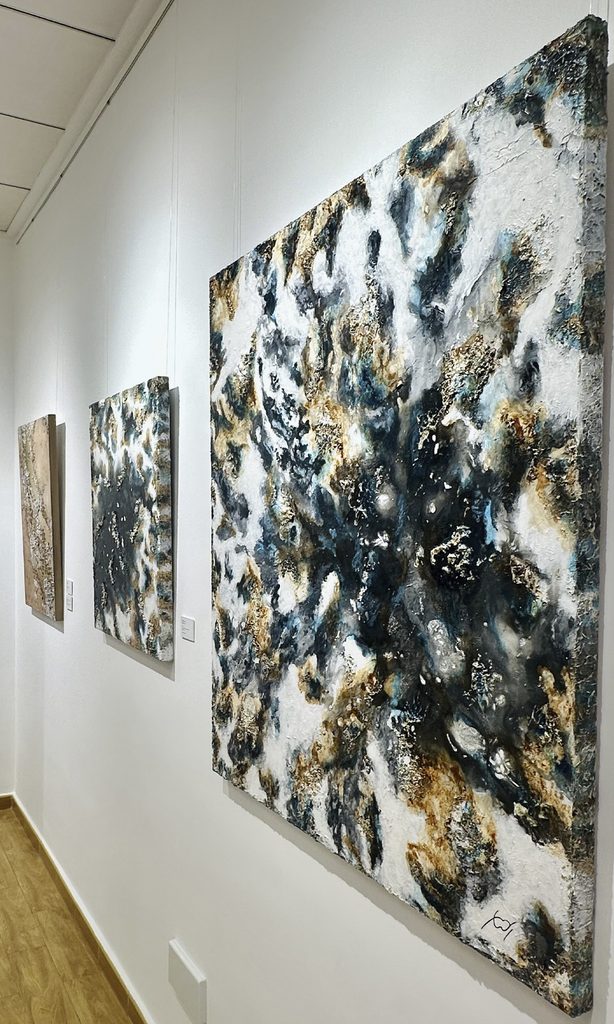 Abstract works featuring textures and reliefs on display on a wall at Mariam Cremades' gallery.