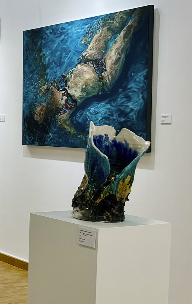 A sculpture with organic forms next to a painting in shades of blue at Mariam Cremades' gallery.