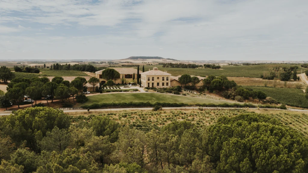 A winery situated on a hill and surrounded by lush vineyards in the Ribera del Duero region.