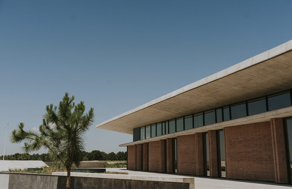 Contemporary facade of Bodegas LA HORRA, featuring brick walls, large windows, and a flat roof.