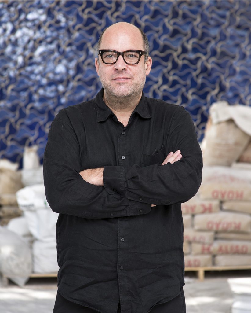 José Noé Suro con lentes y camisa negra, de pie con los brazos cruzados en el interior de Cerámica Suro.