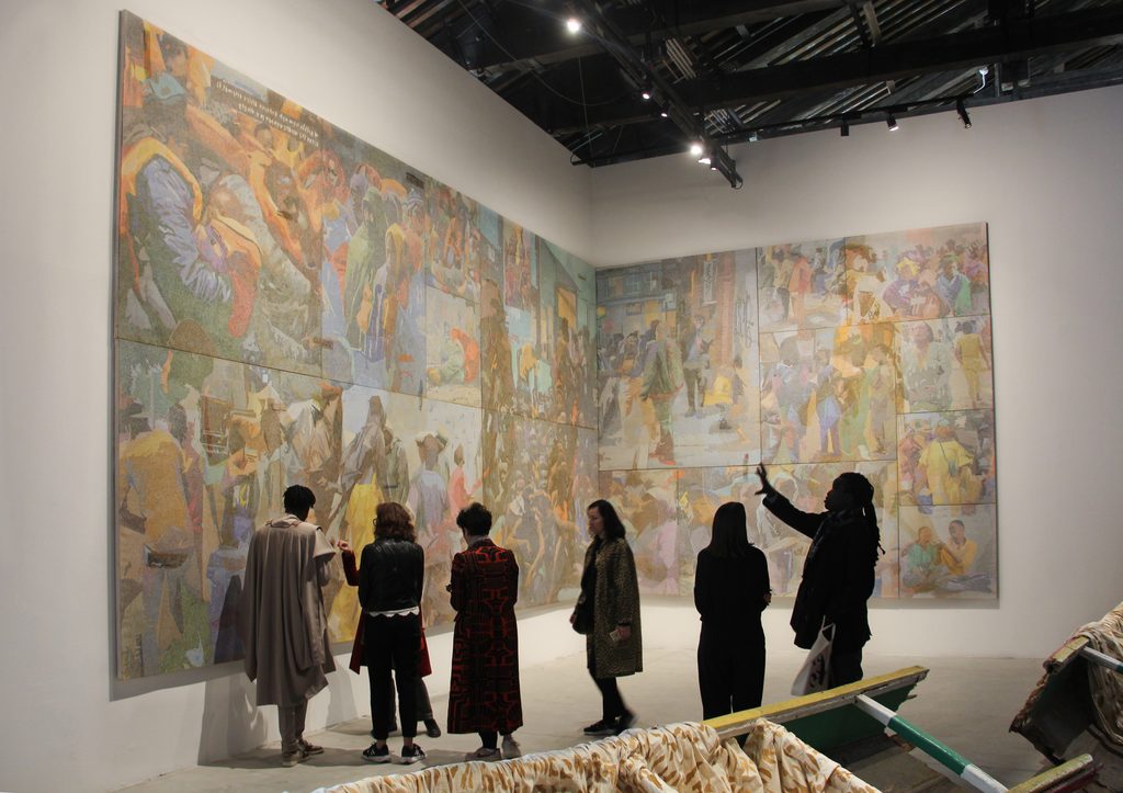 Visitantes frente a una composición pictórica de gran formato en dos paredes del pabellón de Senegal en la Bienal de Venecia.