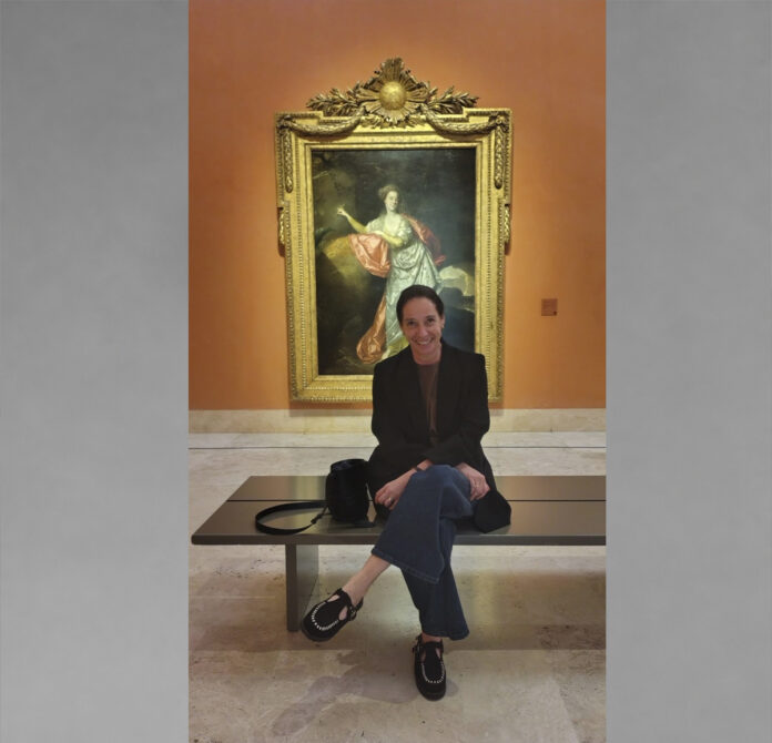 Claribel Terré Morell sentada en una sala de museo, frente a una pintura con marco dorado.