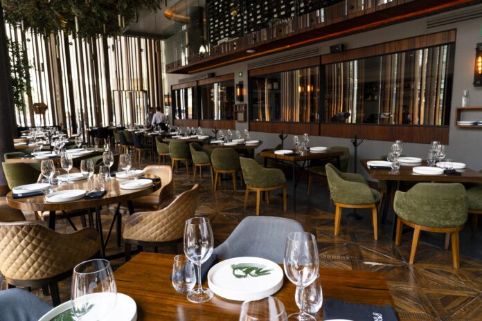 Comedor de Carmela y Sal con mesas de madera y sillas verdes.