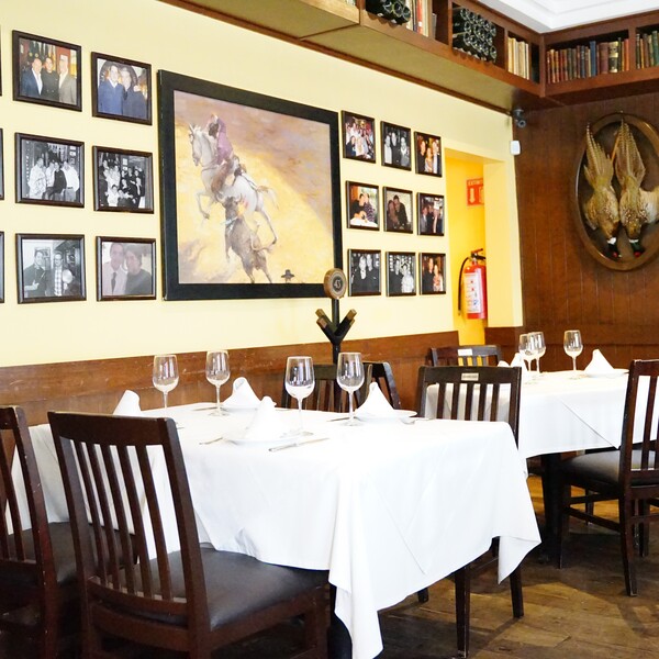 Comedor con manteles blancos, sillas oscuras y cuadros en La Taberna del Chanclas Condesa.